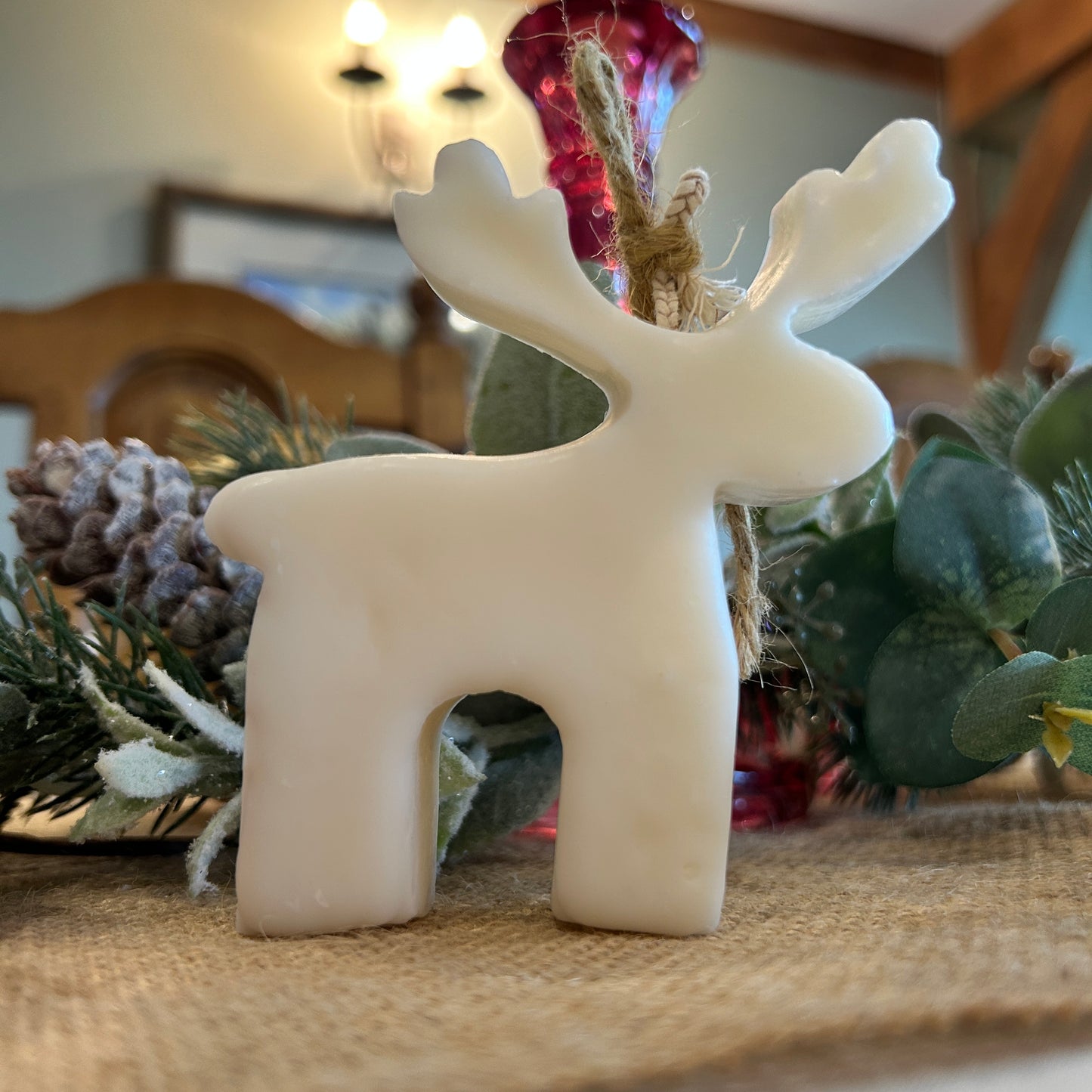 reindeer candle standing in front of Christmas garland and pine cone