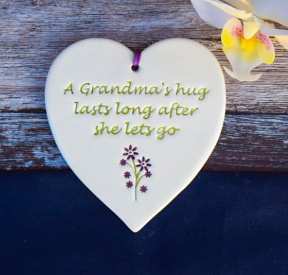 Grandma Ceramic Gift tag, with flower image and the text saying " a grandma's hug lasts ling after she lets go" on wooden board