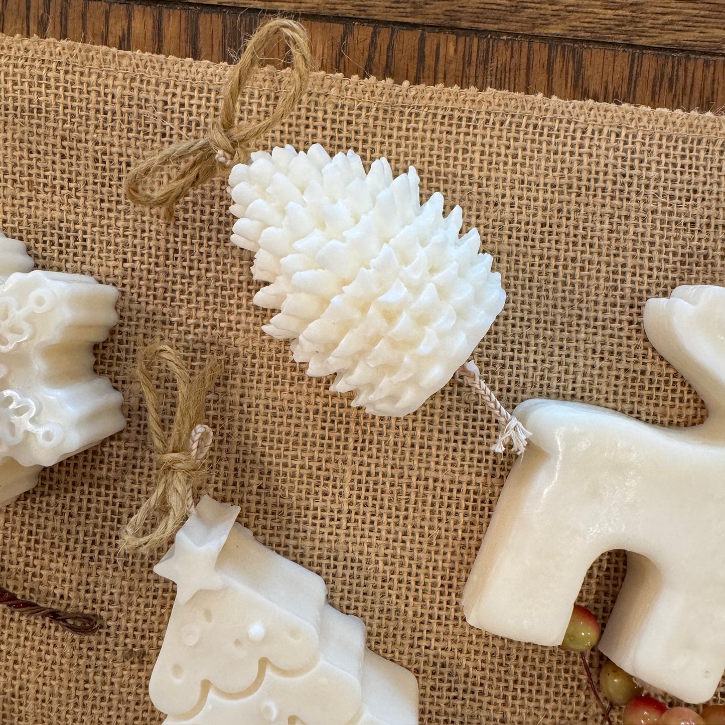 mini Christmas candle selection, includes pine cone, reindeer, Christmas tree and snowflake on hessian sheet