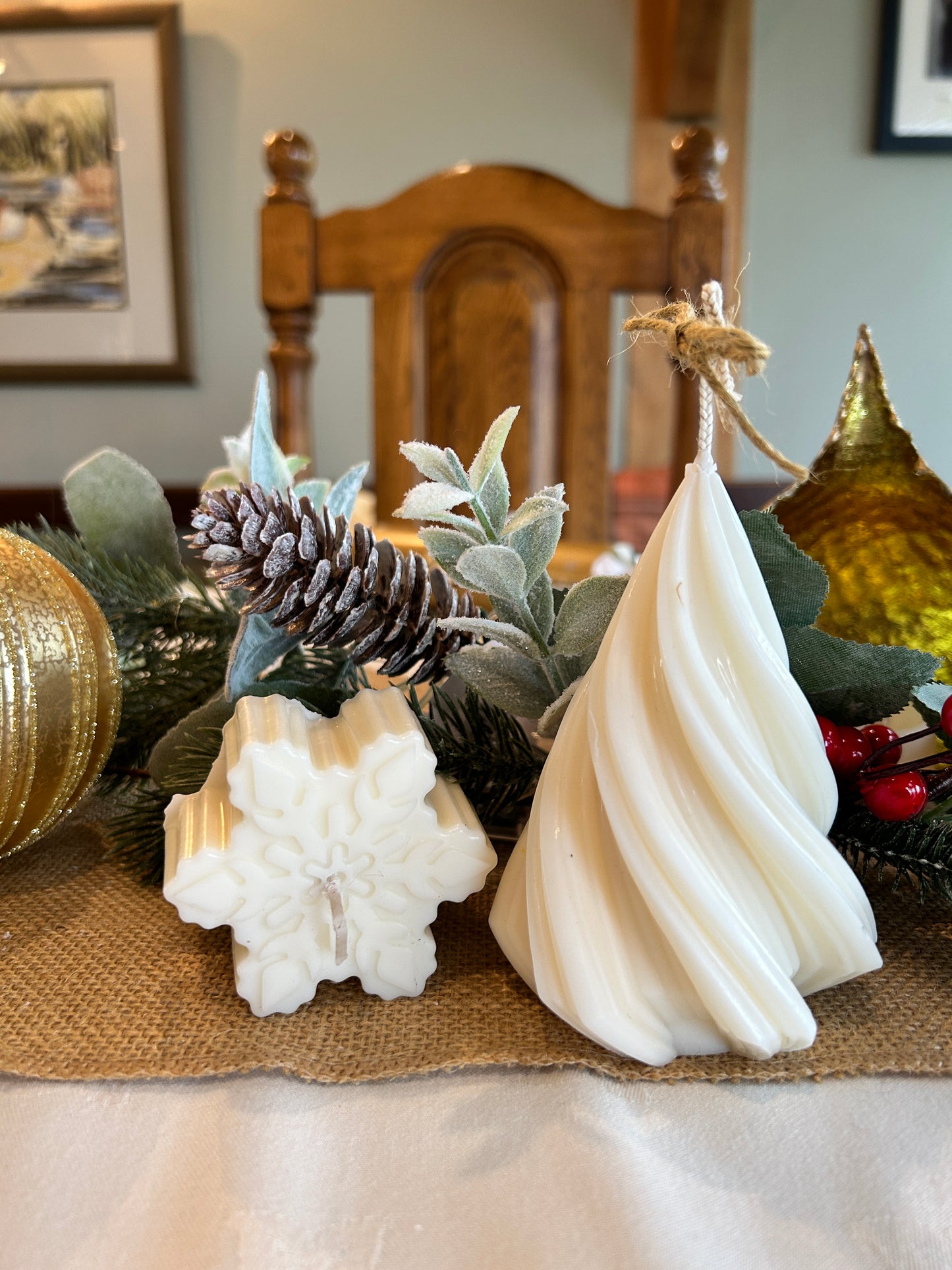 Christmas candles, twisted pillar candles and mini snowflake candles in front of pine cone and Christmas decorations