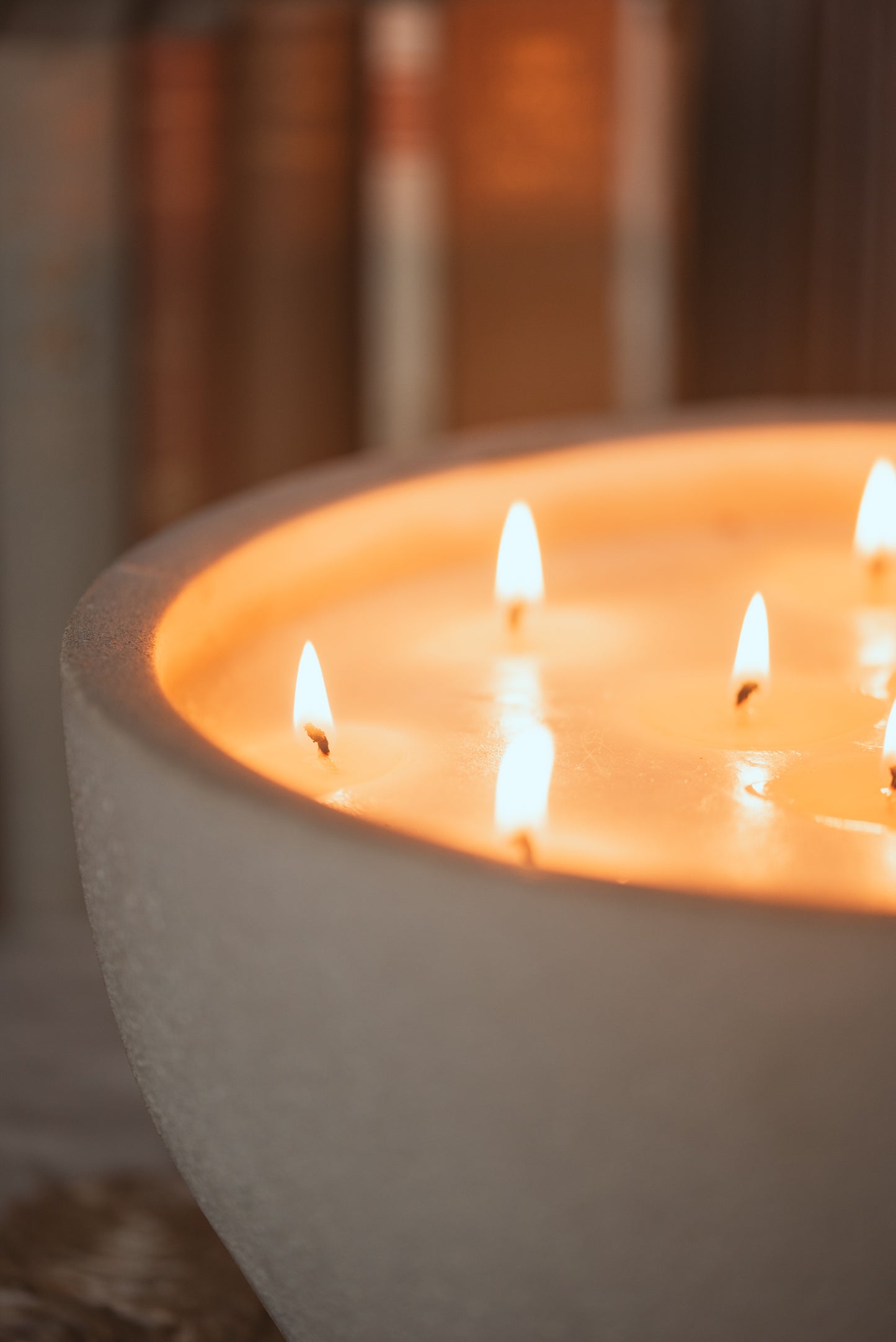close up of bowl candle with wicks lit and books in the background