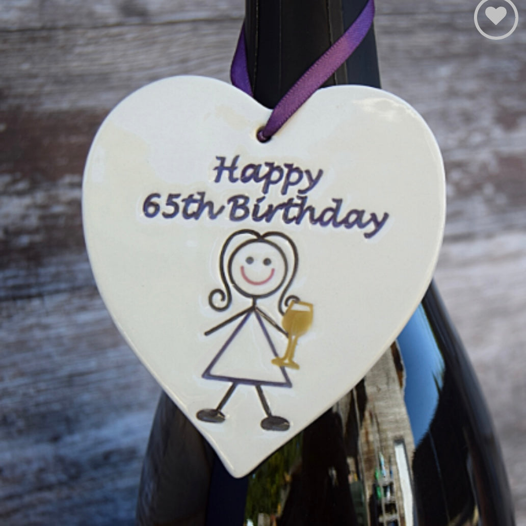 Happy 65th Ceramic Gift Tag with the drawing of a woman drinking and the text "happy 65th birthday"