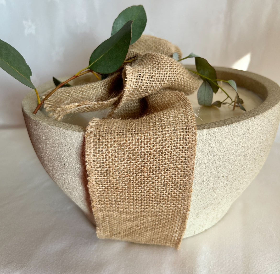 large bowl candle wrapped in a hessian bow with foliage