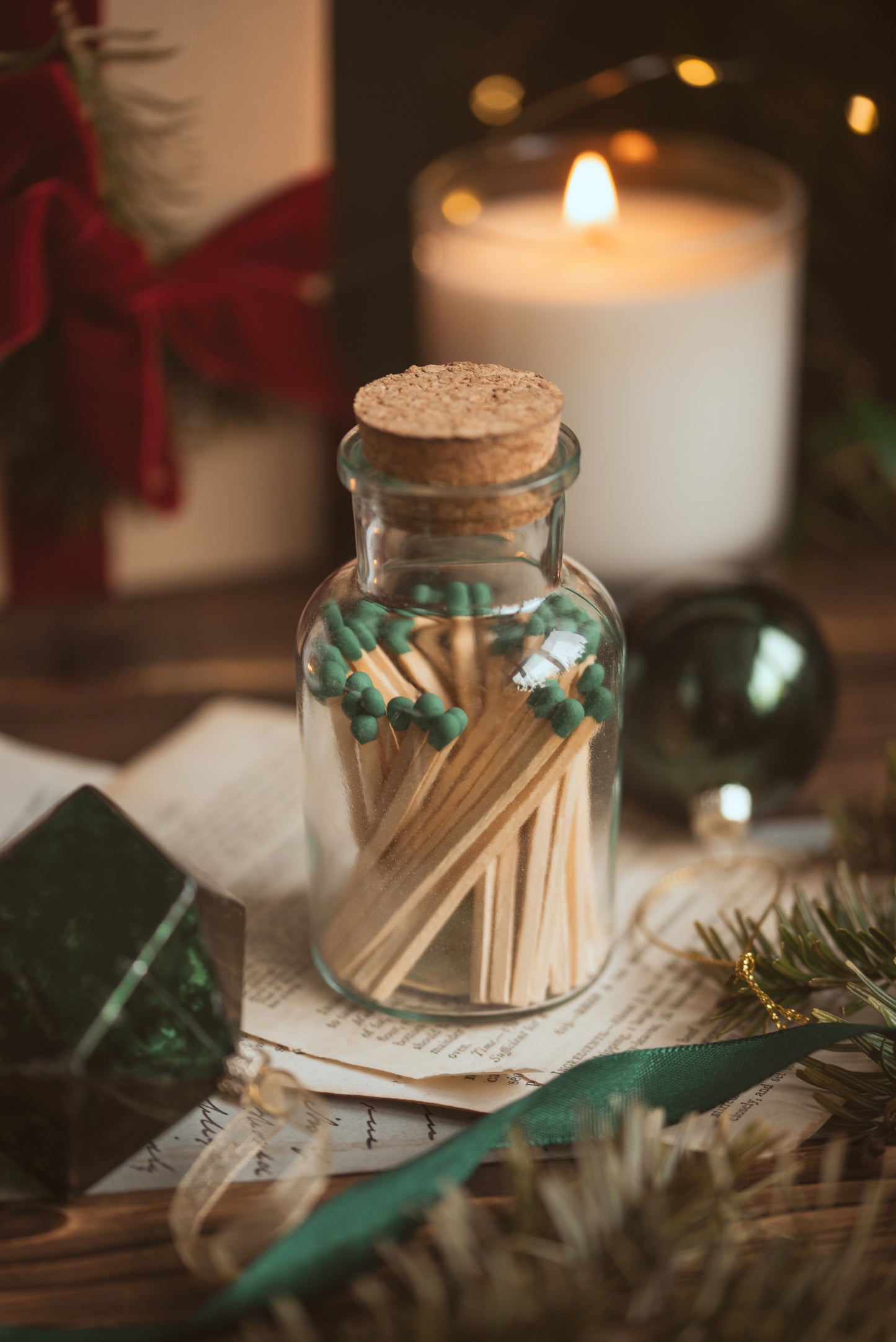 Jar of matches with a lit candle in the background