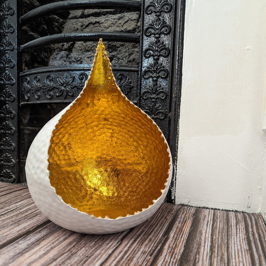 Hammered metal glow bowl reflecting tealight candlelight in a cozy setting