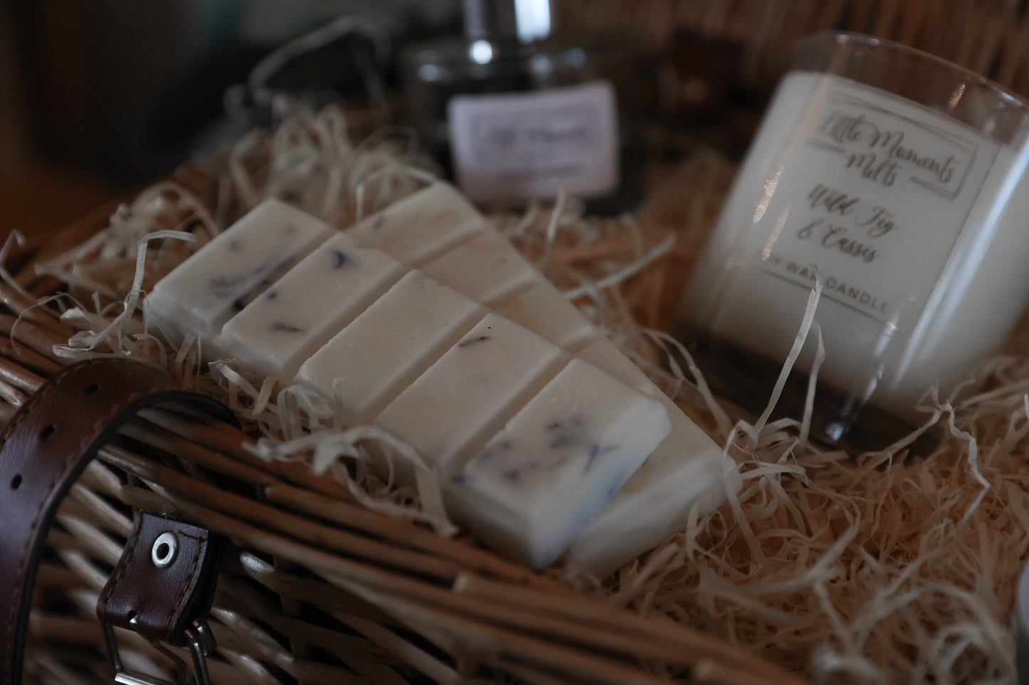 2 x wax melt snap bars surrounded by 2 candles in a camper with shredded wood packaging 