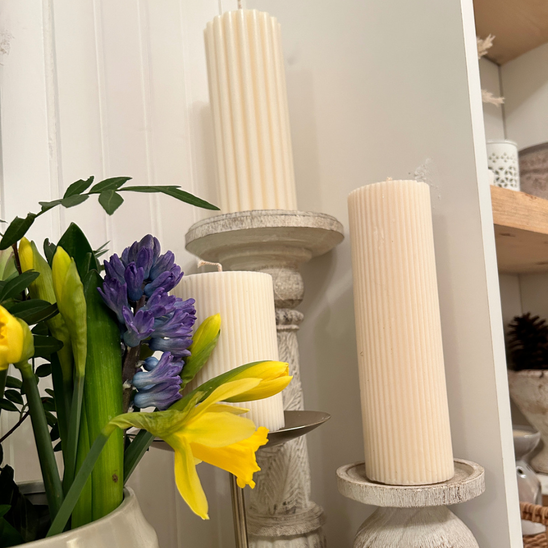 3 x  hand poured soy wax ribbed pillar candles on candle sticks with spring flowers in front 