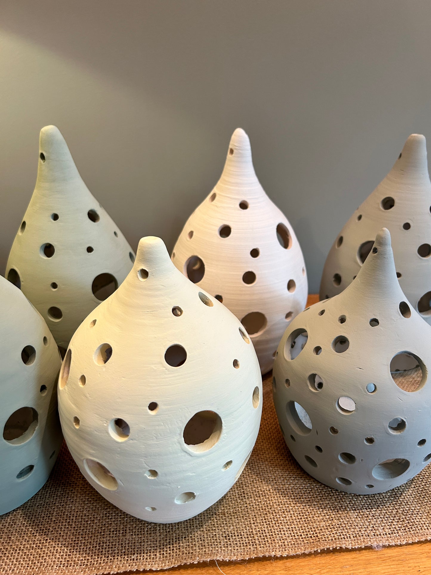 6 pottery lanterns with circles holes across them, 4 in green colour and 2 in white 