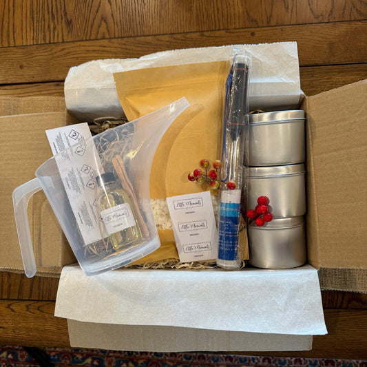 a box of equipment for candle making including a jug, tins, thermometer and labels 