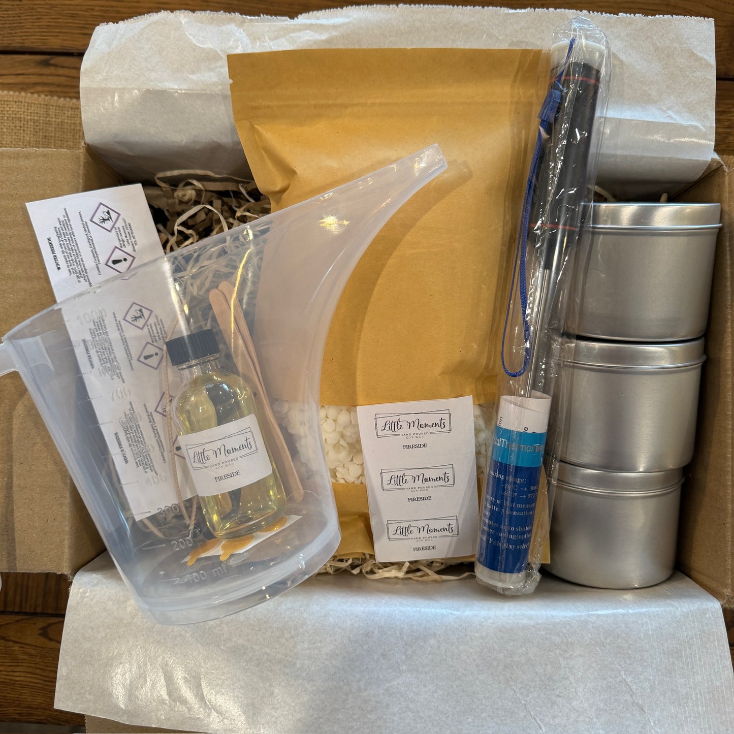 a box of equipment for candle making including a jug, tins, thermometer and labels 