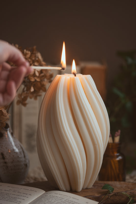 Large sculptural twist pillar candle made from soy wax on styled shelf