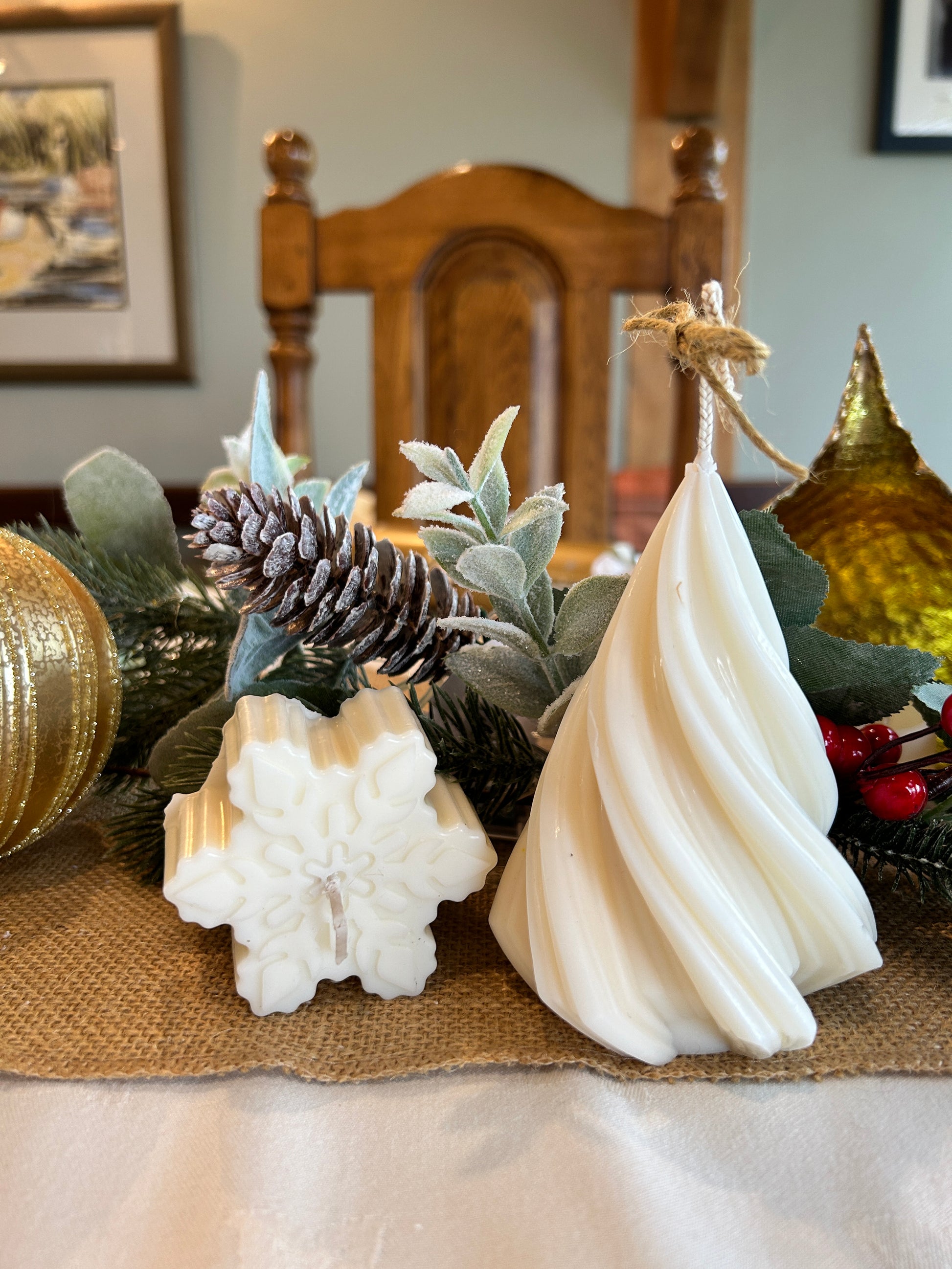 Christmas candles, twisted pillar candles and mini snowflake candles in front of pine cone and Christmas decorations 