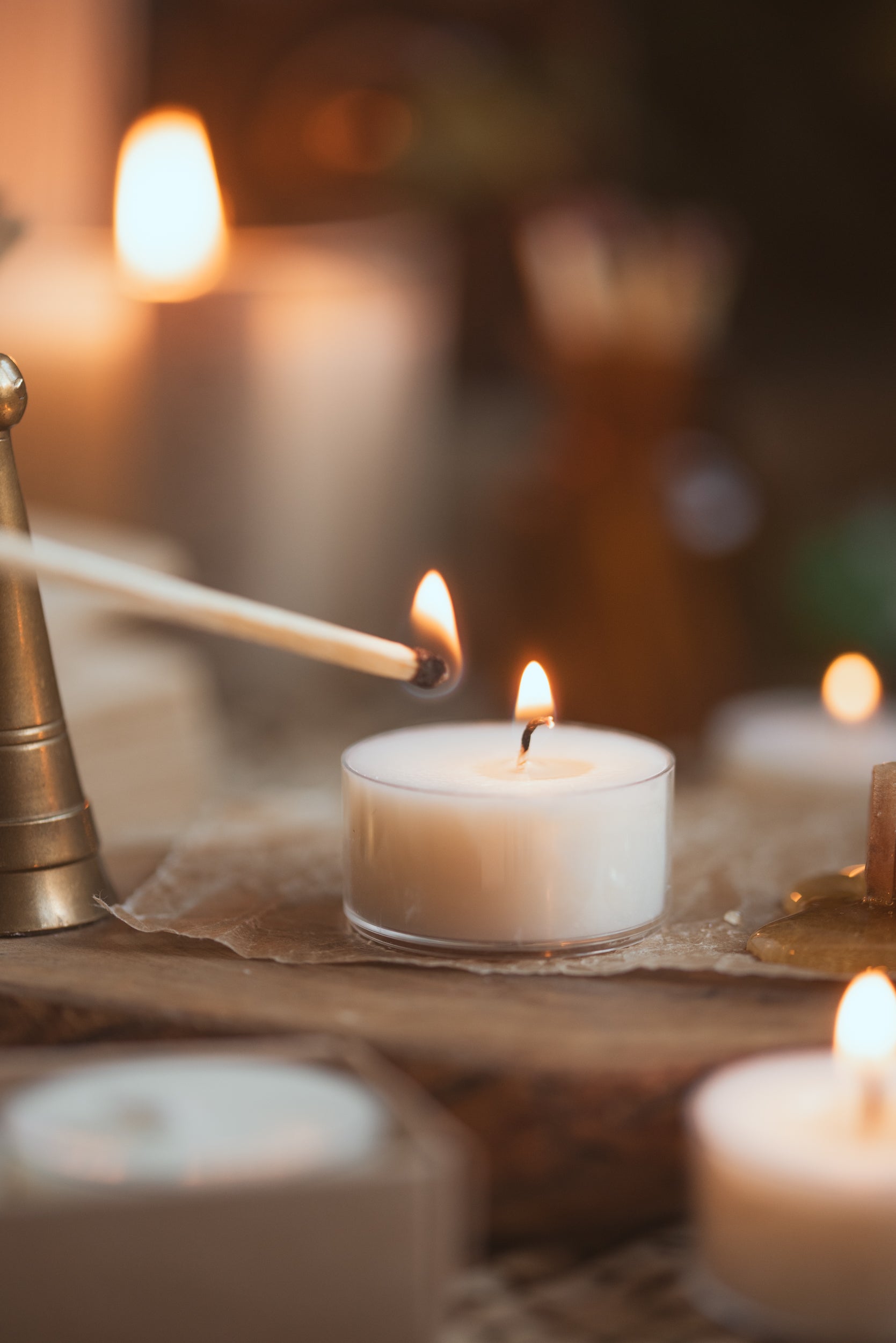 tea light candle lit with lit match near the flame 