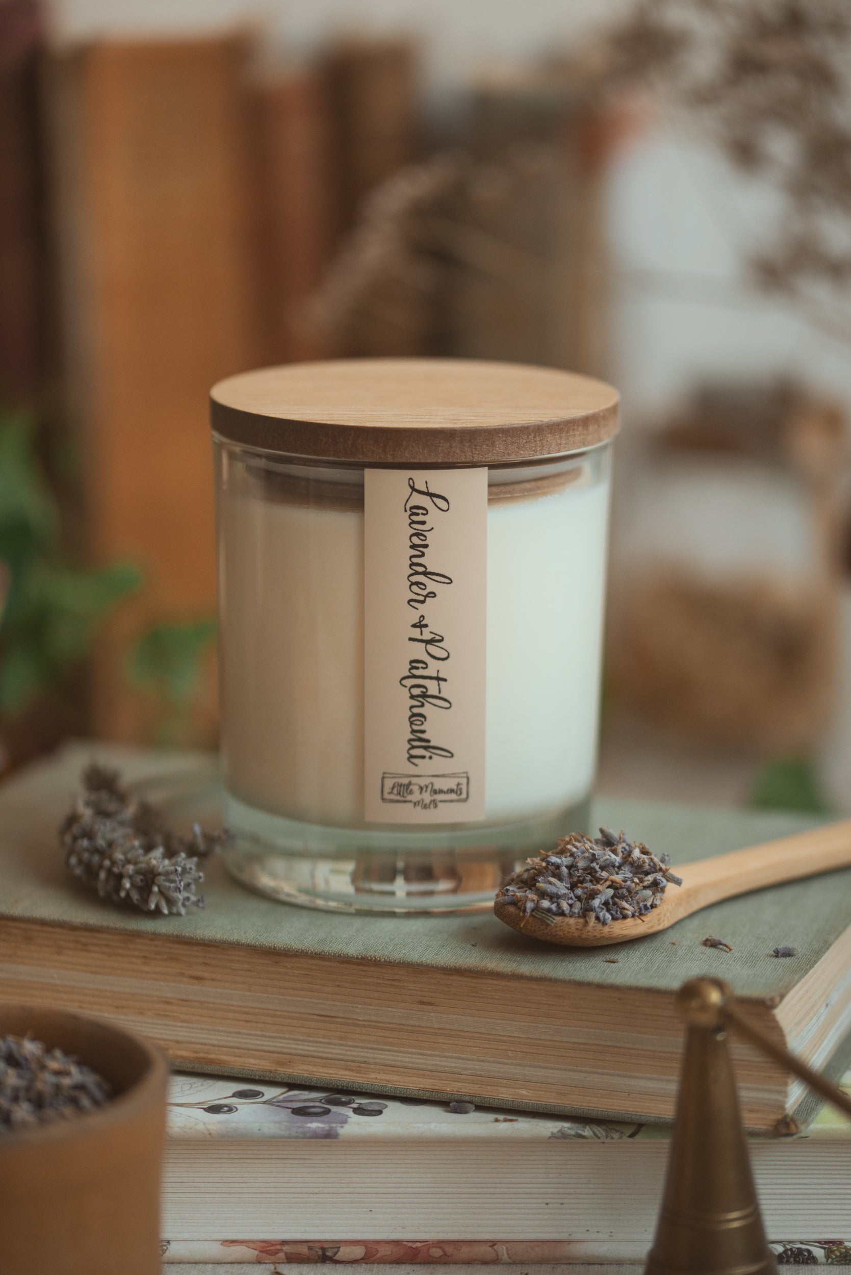 candle in jar with wooden lit, and lavender flowers around the base, all sitting on a book 