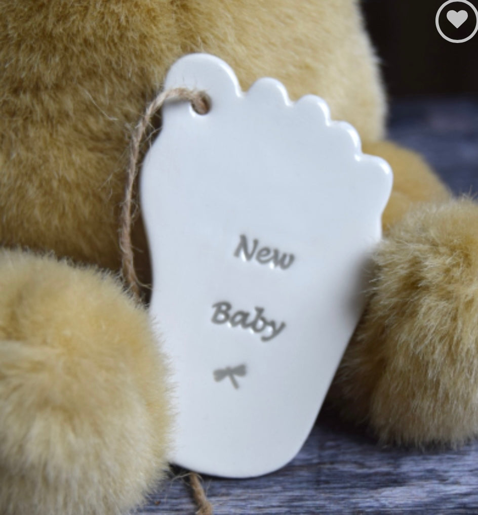 Ceramic tag in the shape of a babies foot with the words "new baby" held upright by a teddy, a perfect  gift for a baby shower, 