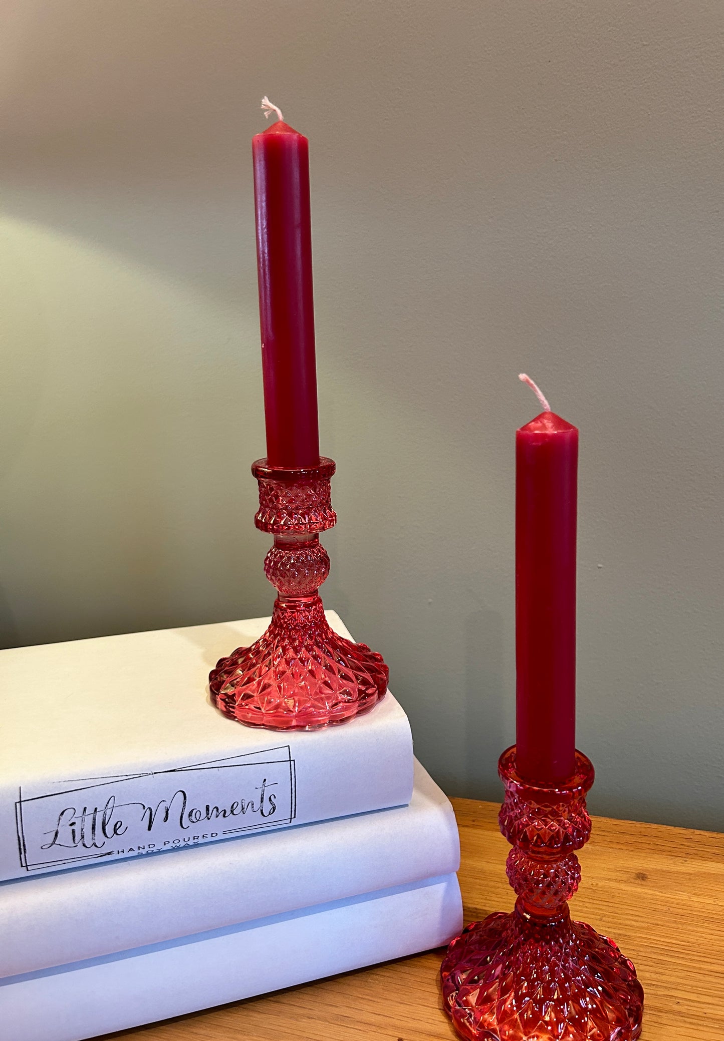 Pink glass  candlesticks  with pink candles, beside 3 books