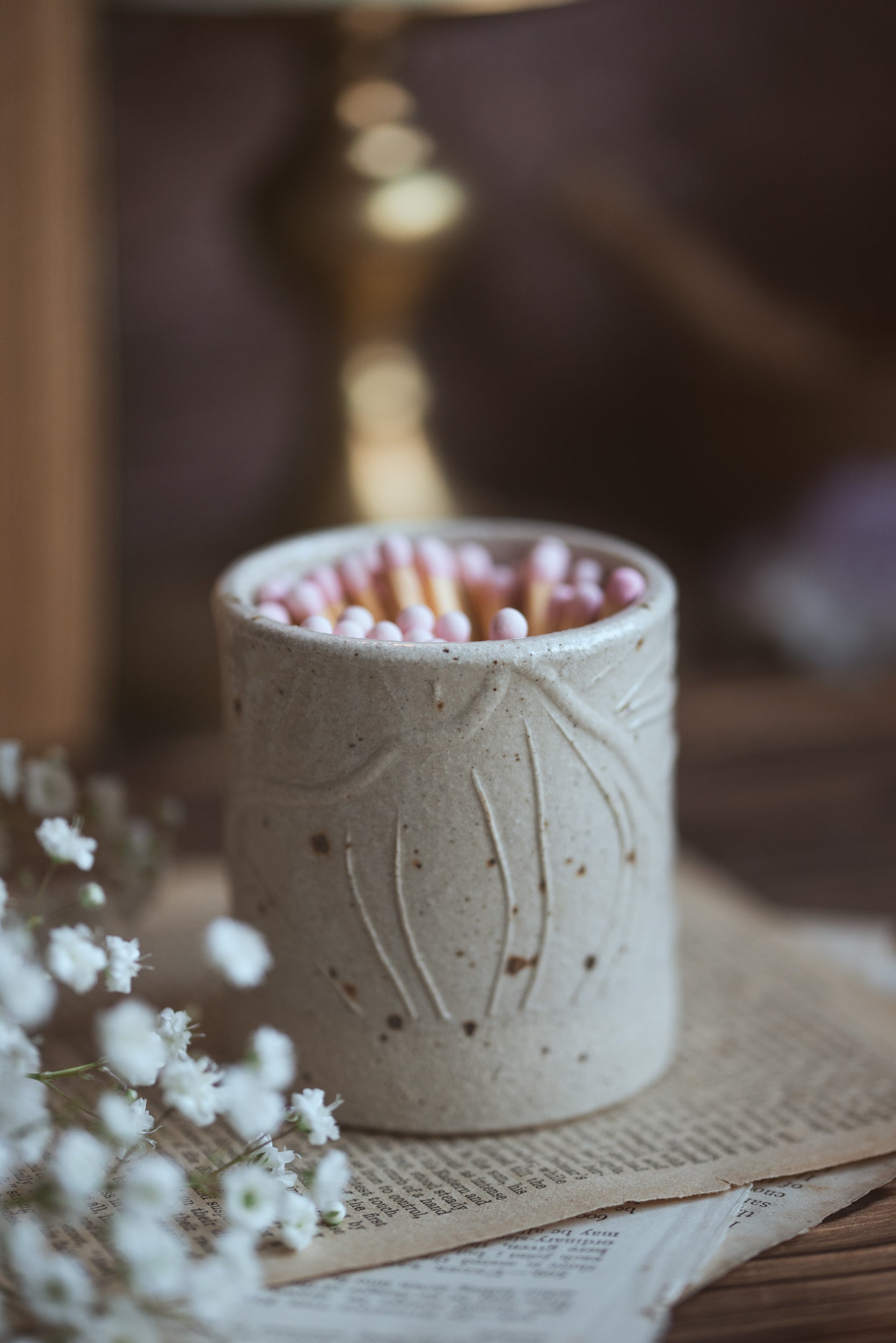 Ceramic match pot with pink safety matches on a wooden surface with a blurred background