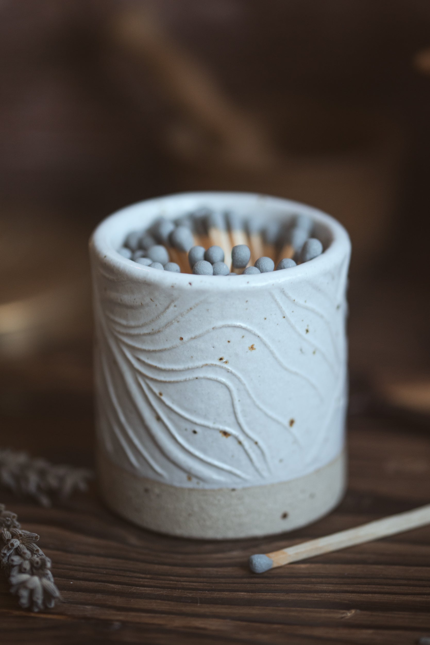 Grey safety matches in a white ceramic matchpot with a blurred background 