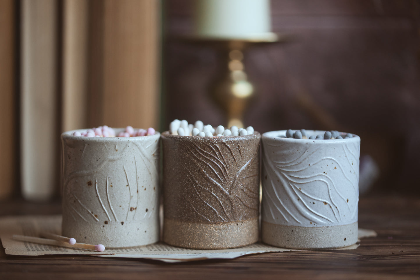 Three ceramic match pots with textured surfaces on a wooden surface.
