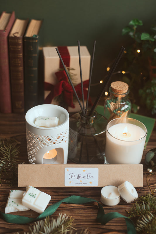 Decorative setup with candles, diffuser, and Christmas-themed items on a wooden surface.