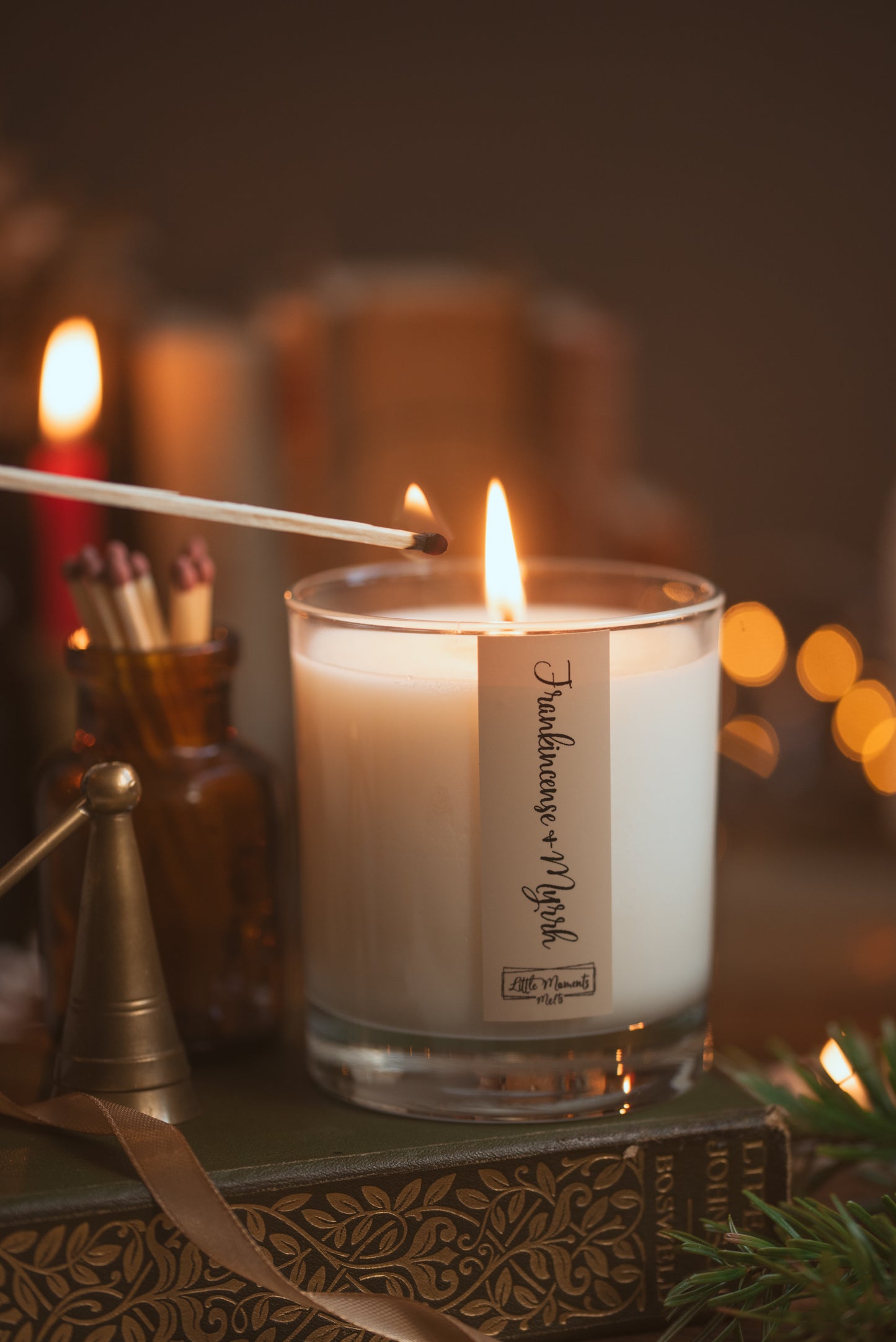 Candle being lit with a match, surrounded by decorative items on a wooden surface.