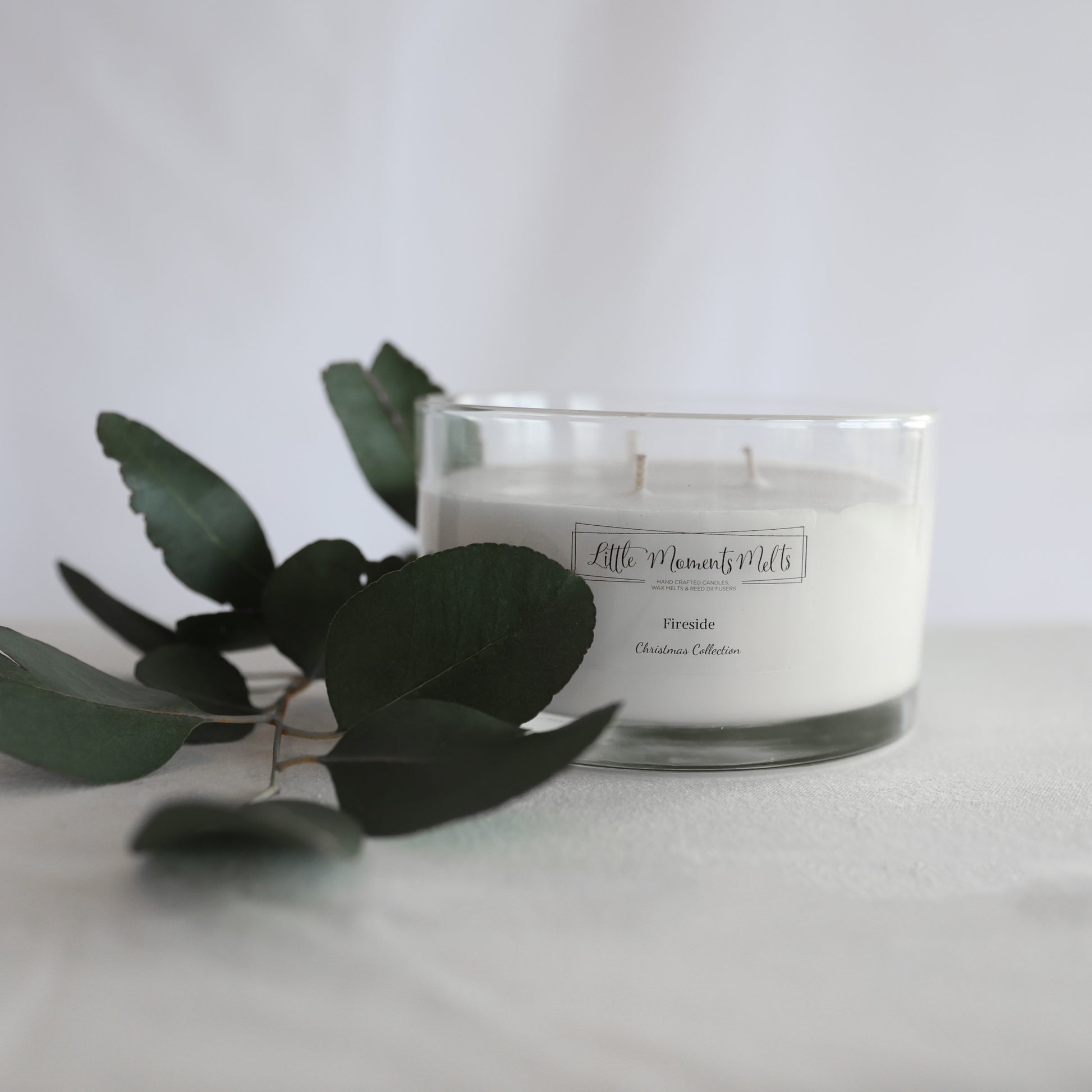 Three-wick soy candle in glass jar with wooden lid, styled on tabletop
